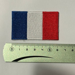 Può includere: Una toppa ricamata della bandiera francese, con i colori blu, bianco e rosso. La toppa è larga circa 5 cm.