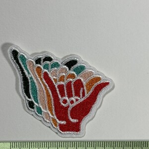 Peut inclure: Un patch brodé coloré à repasser représentant une main faisant le signe shaka, un geste hawaïen populaire de paix, d'aloha et de bonnes vibrations. Le patch mesure environ 5 cm de large.