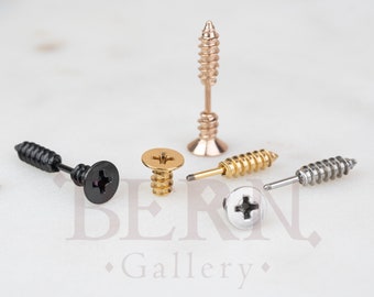 May include: Four screw-shaped earrings in different colors: black, gold, silver, and rose gold. The earrings are all in the shape of a screw with a cross-shaped head.