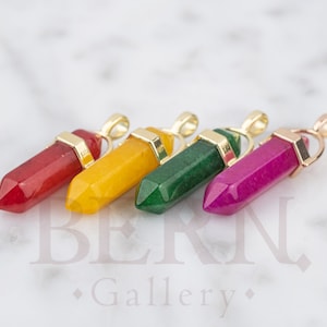 May include: Four gemstone pendants in red, yellow, green, and pink. Each pendant is a pointed crystal shape with a gold-colored metal loop at the top.