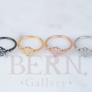 Peut inclure: Quatre anneaux délicats avec un motif de flocon de neige. Les anneaux sont en noir, or, or rose et argent.