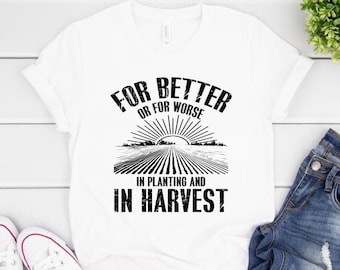 May include: White t-shirt with black text that reads "For Better or For Worse In Planting and In Harvest". The text is surrounded by a graphic of a field of crops and a sun.