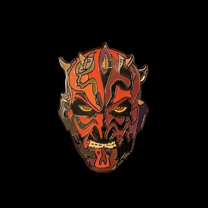 May include: A red, black, and purple enamel pin featuring a detailed illustration of Darth Maul's face.
