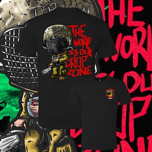 May include: Black t-shirt with a cartoon illustration of a soldier wearing a helmet and holding a chainsaw. The text "The world is our drop zone" is printed in red on the shirt.