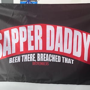 Puede incluir: Pancarta negra y roja con el texto "SAPPER DADDY BEEN THERE, BREACHED THAT BROVEMBERS".