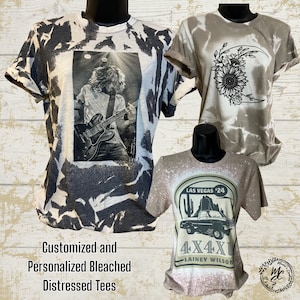 Puede incluir: Tres camisetas desgastadas en maniquíes. Una presenta una imagen en blanco y negro de un músico tocando la guitarra. Otra tiene un diseño de girasol y media luna. La tercera tiene un gráfico de Las Vegas y el texto "4X4X1".