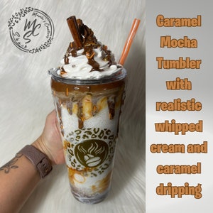 May include: Caramel Mocha Tumbler with realistic whipped cream and caramel dripping. The tumbler has a brown and gold leopard print design with a coffee cup logo.