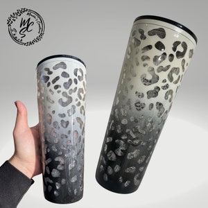 May include: Two stainless steel tumblers with a black and white ombre leopard print design. Both tumblers are insulated and have a black lid.