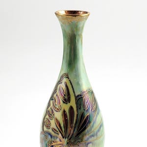 May include: A pearlescent green vase with a butterfly design. The vase has a slender neck and a bulbous body. The butterfly design is in shades of purple, gold, and brown. The rim and base are trimmed with gold.