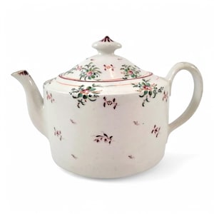 Puede incluir: Tetera de porcelana blanca con un patrón floral en tonos rosa, verde y marrón. La tetera tiene una tapa con un pomo en la parte superior.