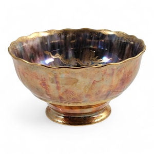 May include: A decorative silver bowl with a scalloped rim and a pedestal base. The bowl has a gold-colored rim and base, with etched floral and scroll designs. The interior has a dark, iridescent finish.