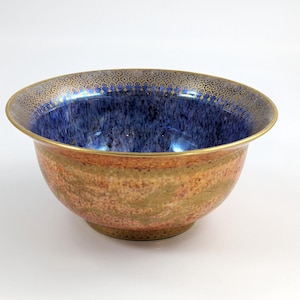 May include: A large, round bowl with a blue and gold glaze. The bowl has a textured, speckled surface and a gold rim with a decorative pattern.