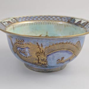 May include: A blue and white porcelain bowl with a gold dragon design. The bowl has a scalloped rim and a delicate floral pattern.