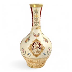 May include: A white ceramic vase with a wide, round body and a long, narrow neck. The vase is decorated with intricate floral patterns, including a central medallion featuring a figure in a red and gold frame. The vase has a gold rim and a base with a raised design.