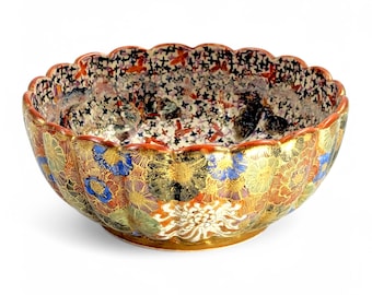 Könnte beinhalten: Eine große, runde Keramikschale mit einem gewellten Rand. Die Schale ist mit einem farbenfrohen Blumenmuster in Rot-, Blau-, Grün- und Goldtönen verziert. Die Schale ist im japanischen Stil gefertigt.