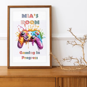 May include: A colourful gaming controller with paint splatters, a wooden frame, and the text "MIA'S ROOM Gaming in Progress".