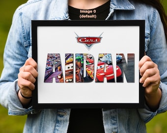 May include: A black framed print with a white background featuring the Cars logo and the name "AIDAN" spelled out in large letters with images of cars from the movie Cars inside each letter.