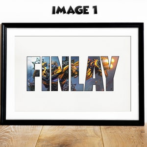 May include: A framed print featuring the name "FINLAY" in large letters. The letters are filled with an image of a yellow and black robot character from a science fiction film.