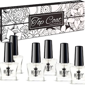 May include: A collection of clear nail polish bottles with black lids, displayed in front of a patterned box. The box is black and white and reads "Top Coat Nail Polish Set". The bottles are branded "BEAUTY BRITAIN".
