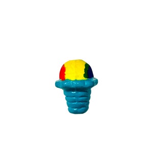 May include: A colorful, miniature snow cone figurine. The top is a vibrant mix of red, yellow, and blue, while the base is a bright turquoise. The figurine is set against a plain white background.