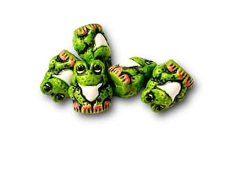 Puede incluir: Cinco figuritas de cerámica verde de ranas con vientres blancos y patas rosadas. Las ranas están dispuestas en un grupo.