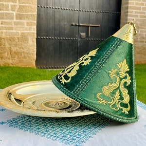 May include: A gold serving tray with a green velvet lid with gold embroidery. The lid has a cone shape and a gold handle on top.