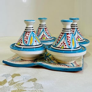 May include: Set of four small blue and white ceramic tagines with red and yellow accents, arranged on a matching blue and white patterned tray.