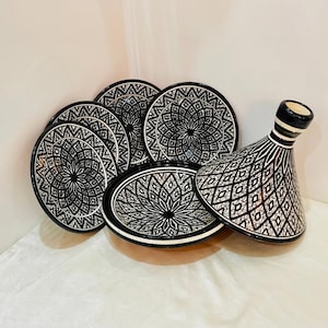 May include: A set of black and white ceramic serving dishes with intricate geometric patterns. The set includes a large round dish with a lid, and several smaller round dishes.