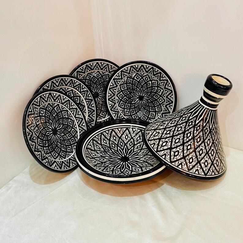 May include: A set of black and white ceramic serving dishes with intricate geometric patterns. The set includes a large round dish with a lid, and several smaller round dishes.