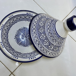 May include: A white ceramic serving dish with a blue and white geometric pattern. The dish has a lid with a knob on top.