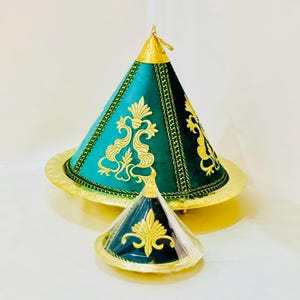 Könnte beinhalten: Zwei grüne und goldene marokkanische Tagine mit aufwendigen Blumenstickereien. Die größere Tagine hat einen breiten, runden Boden und einen konischen Deckel. Die kleinere Tagine ist ähnlich im Design, aber kleiner.