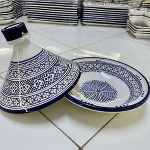 May include: A white ceramic serving dish with a blue and white geometric pattern. The dish has a lid with a pointed top. The dish is a traditional Moroccan tagine.