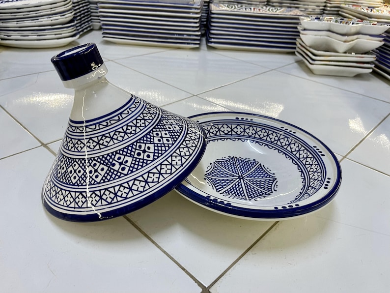 May include: A white ceramic serving dish with a blue and white geometric pattern. The dish has a lid with a pointed top. The dish is a traditional Moroccan tagine.