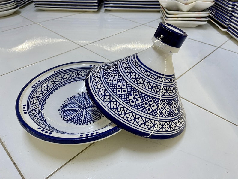 May include: A white ceramic serving dish with a blue and white geometric pattern. The dish has a lid with a pointed top. The dish is perfect for serving Moroccan food.