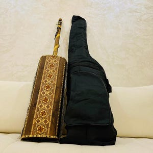 May include: A traditional wooden musical instrument with intricate inlaid designs, featuring a long neck and a cylindrical body. It is accompanied by a black padded carrying case.
