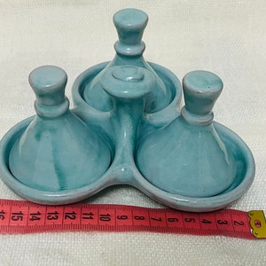 May include: A set of three light blue ceramic condiment dishes with lids. The dishes are arranged in a circle and have a raised centre piece.