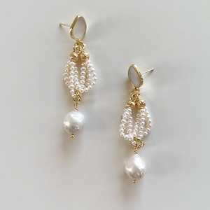 May include: A pair of gold-tone drop earrings featuring a white stone stud, a cluster of small white seed pearls arranged in a loop, and a single larger white baroque pearl dangling at the bottom, all connected by gold-tone metal hardware.