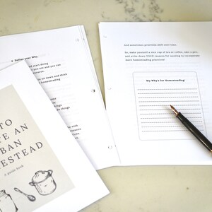May include: A white guide book titled "How to Create an Urban Homestead" with a drawing of a pot, a jar, and a spoon. The book is open to a page with the title "My Why's for Homesteading" and a lined space for writing.