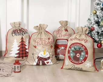 May include: Four burlap Christmas gift bags with red trim and drawstring closures. Designs include a Christmas tree, snowman, and a reindeer with the text "No Peeking! Delivered by Rudolph Donna".