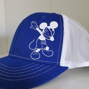May include: A blue and white baseball cap with a white cartoon image of Mickey Mouse doing the "dab" pose.