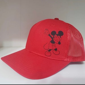 May include: Red and black baseball cap with a mesh back. The front of the cap features a black and white image of Mickey Mouse doing the dab.