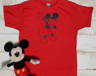 Peut inclure: T-shirt rouge avec une image en noir et blanc de Mickey Mouse faisant le dab. Le t-shirt est de taille enfant.