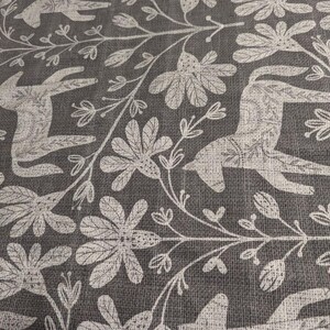 May include: A grey fabric with a white repeating pattern of stylised animals and floral designs. The animals resemble deer or horses with long legs and necks.