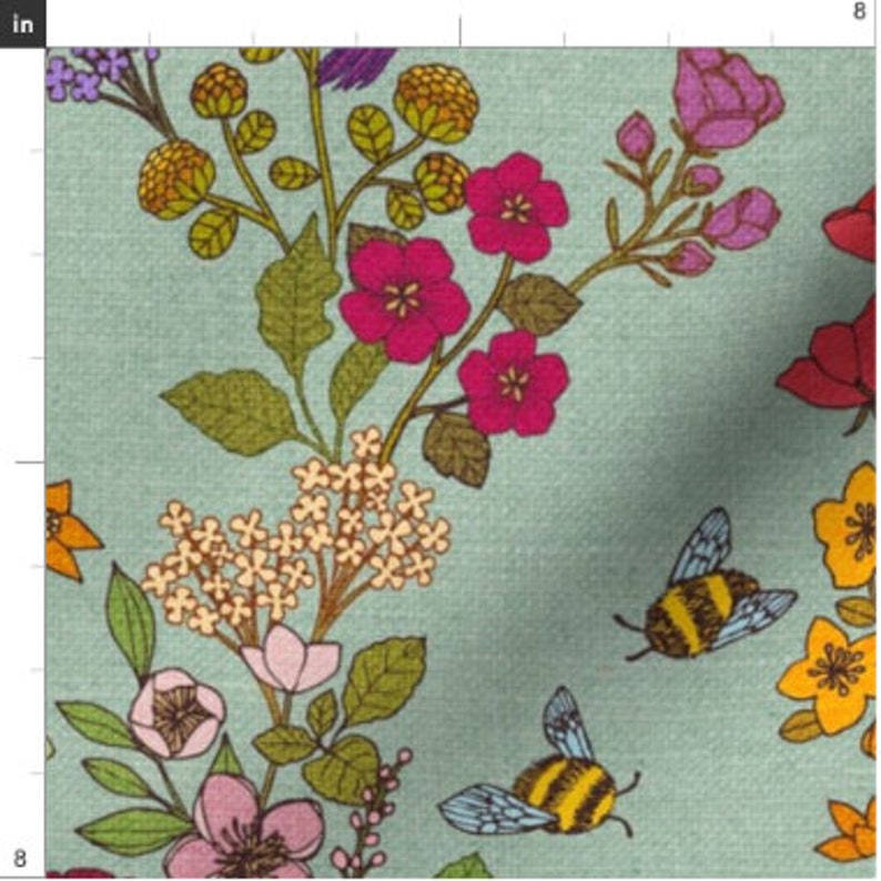 Op de afbeelding: Een tealblauwe stof met een bloemenpatroon met roze, gele en oranje bloemen, groene bladeren en twee hommels.