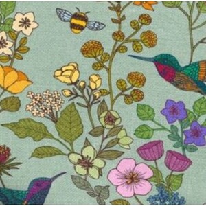 Op de afbeelding: Een tealblauwe stof met een bloemenpatroon met kolibries, bijen en bloemen in tinten geel, roze, paars en groen.