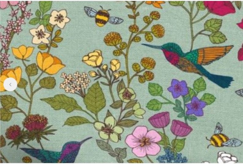Op de afbeelding: Een tealblauwe stof met een bloemenpatroon met kolibries, bijen en bloemen in tinten geel, roze, paars en groen.