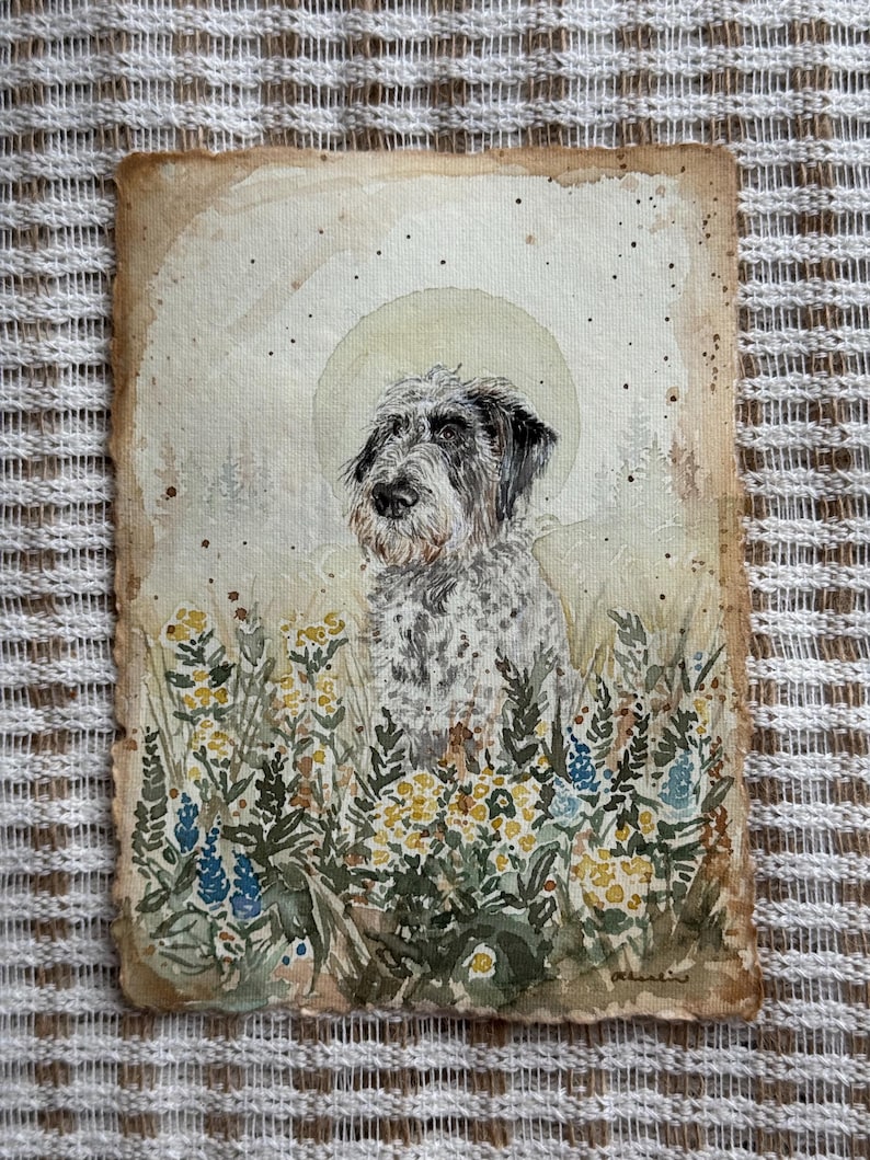 以下が含まれることがあります： 黒と白の毛並みの犬の水彩画。黄色と青色の野草の野原に設定されています。このアートワークは、明るい色の背景と太陽のような光輪を備えたヴィンテージ感があります。