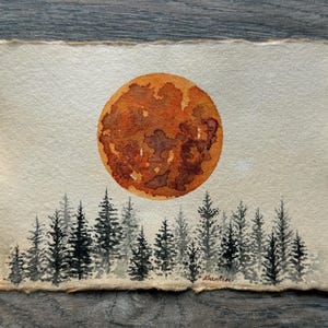 May include: Watercolor painting of a large orange moon rising over a dark forest of trees. The moon has a textured surface and is painted in shades of orange, brown, and red. The trees are painted in shades of black and gray.