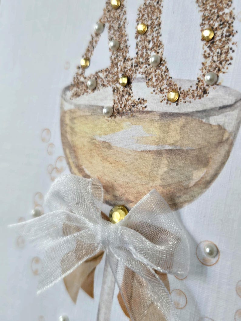May include: A handmade greeting card featuring a champagne glass illustration with the number "40" in gold glitter and embellished with pearls and gold gems. A white sheer bow is attached to the glass, adding a touch of elegance. The card is perfect for a 40th birthday celebration.
