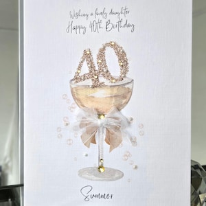 May include: A birthday card with a champagne glass design. The card reads "Wishing a lovely daughter Happy 40th Birthday" and includes the name "Summer". The number "40" is decorated with glitter.